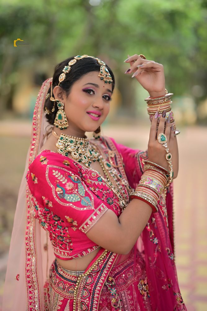 Bride posing in pink lehenga with polished bridal makeup