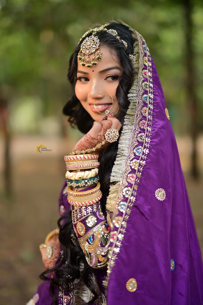 A bride in violet with gold jewellery and soft glam makeup